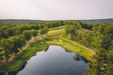 Bereketli yeşil golf sahasının havadan görünüşü sakin mavi su gövdesini çevreledi.