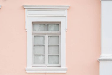 Window framed by white trim on pink wall