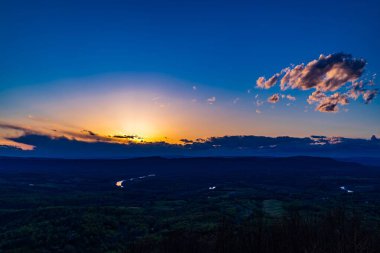 Gün batımının dramatik bulutlarla dağlık arazide panoramik görüntüsü
