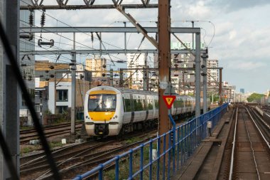 Tren, bulutlu gökyüzünün altındaki tren rayları boyunca yaklaşıyor.