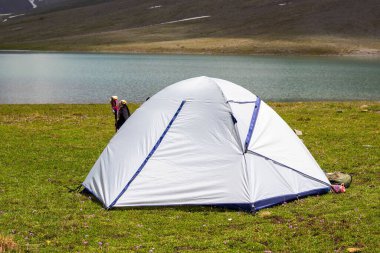Sakin mavi gölün yanında beyaz çadır kuran biri var.