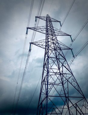 Elektrik hatları olan bulutlu gökyüzüne karşı yüksek elektrik kulesi