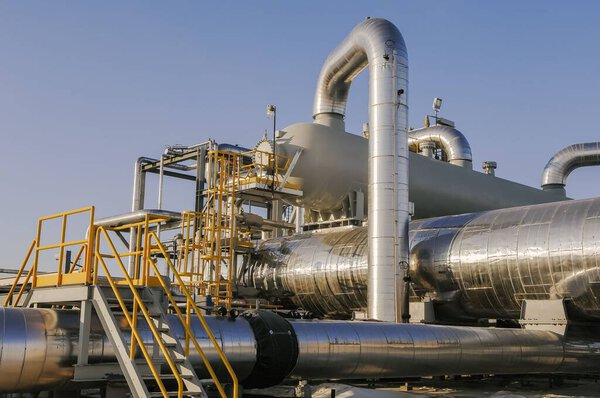 Внешний крупный план промышленных трубопроводов, теплообменников и лестниц доступа