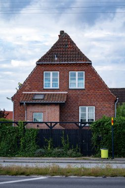 Yeşil çalılar ve ağaçlarla çevrili kırmızı tuğla ev