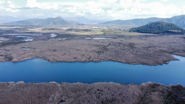 Hava manzarası mavi göl ve kayalık arazi ile geniş bir manzara gösteriyor.