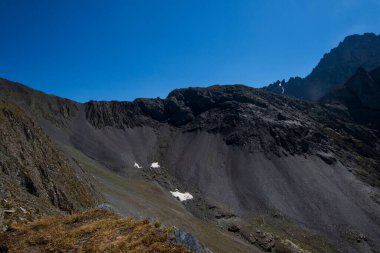 Blue Sky 'ın altında Dark Scree ve Rocky Cliffs ile dik Alp yamaçları