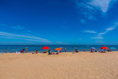 İnsanlar ve renkli şemsiyelerle kumsalda güneşli bir gün