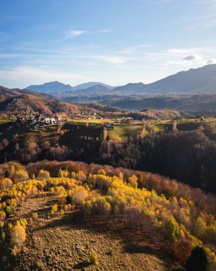 Aerial View of a Small Mountain Village Surrounded by Autumnal Forests