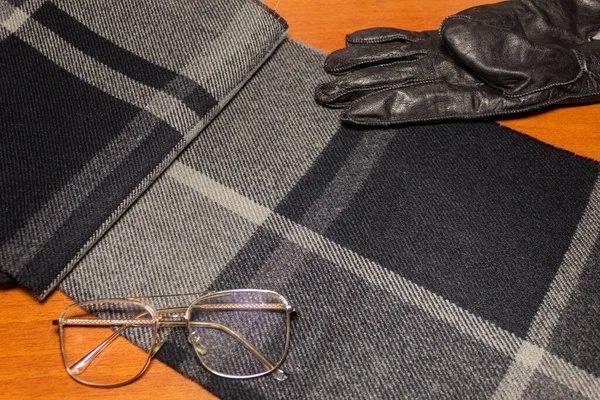 木製のテーブルの上に男の異なる衣類アクセサリー グレー メガネと革の手袋の異なる色合いを持つ小切手スカーフ — ストック写真