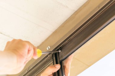 Pencere vidasını tornavidayla ayarlayan bir adam.