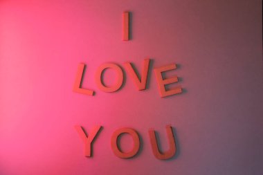 Love sign made with letters on a wall illuminated by a pink light. Text: I love you
