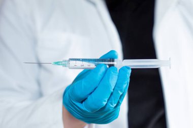 An unrecognizable doctor holding a syringe horizontally