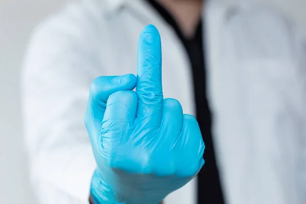 Unrecognizable doctor raising the middle finger
