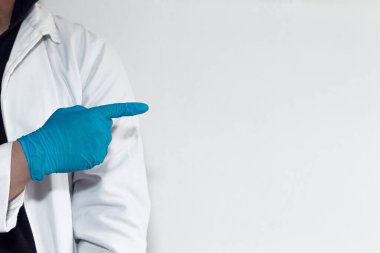 Unrecognizable doctor pointing at a white wall
