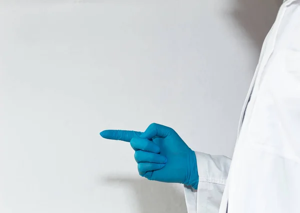 Unrecognizable doctor in profile pointing at a white wall