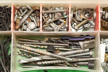 Top view of a small toolbox filled with screws and bits of different sizes