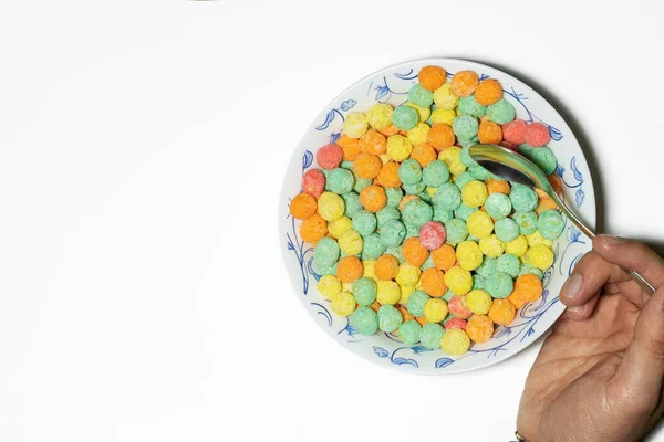 Overhead shot of man eating breakfast from a bowl of colorful sugary cereal on a white background