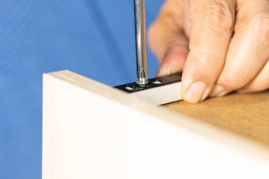 A man putting a screw in the wheel support of a drawer