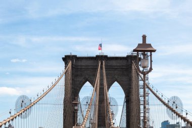 An arch of the Brooklyn Bridge with blue sky in the background on a sunny day