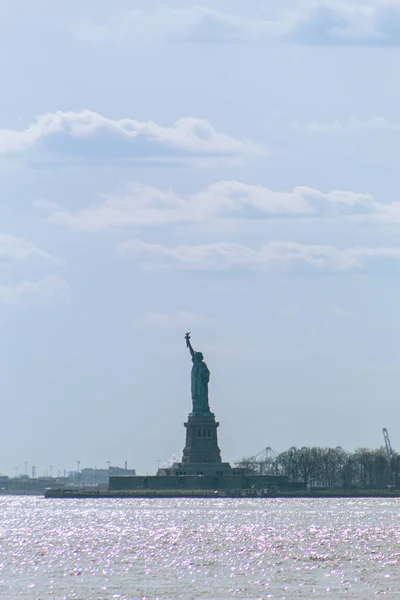 Statue of Liberty seen from afar with blue sky in the background, Iconic American Monument on Liberty Island on the Hudson River
