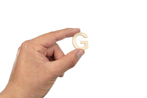 白い背景に孤立した小さな木製の文字Gを保持する人の手の閉じる — ストック写真