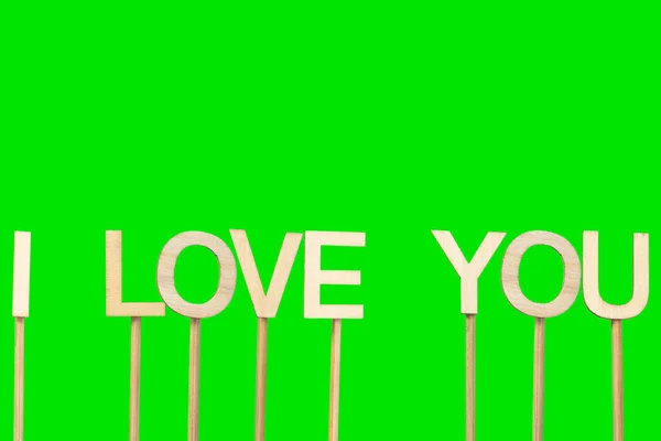 I love you sign made with individual wooden letters on a green chroma background.