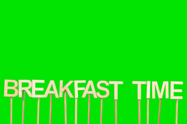 Breakfast time sign made with individual wooden letters on a green chroma background.
