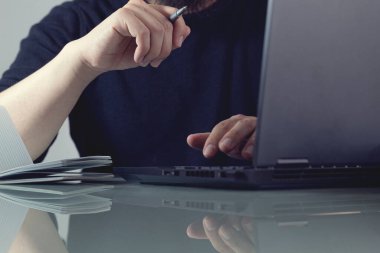 Piyasayı analiz eden bir dizüstü bilgisayarın önünde not almaya hazırlanan bir iş adamı. Toplantı toplantı odasında. İş ve girişimcilik kavramı.