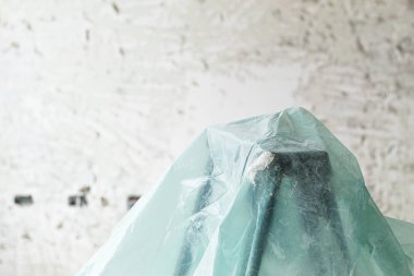 Kabuk soyma duvarının önünde yeşil bir plastikle kaplı bir merdiven ve odağı olmayan delikler. inşaat arkaplanı.