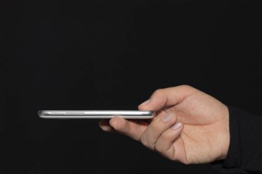Siyah arka planda ekranı olan bir akıllı telefonu tutan. Kopyalama alanı olan resim. Teknoloji konsepti.