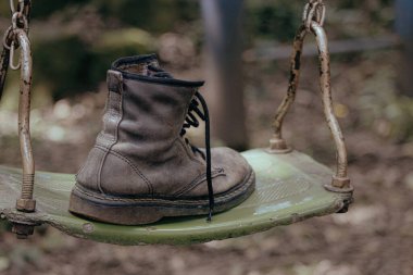 Sonbaharda parkta salıncakta terk edilmiş eski bir bot. Kayıp kişi. Silahlı çatışma. Kıyafet ve ayakkabı konsepti.