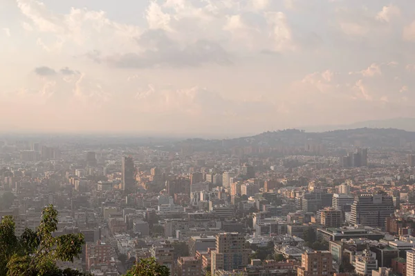 Bogota seen from a mountain. A city polluted with smog seen in a sunset. Busy streets, skyscrapers and mountains of a Latin city.