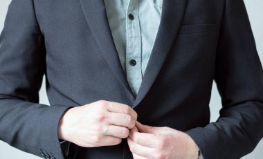 Ceketinin düğmelerini iliklemeyen takım elbiseli bir yönetici. İş adamı giyiniyor. Kişisel sunum kavramı.