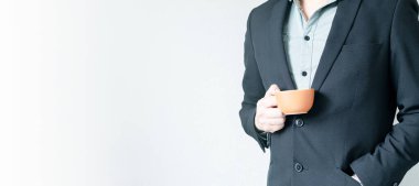 Elinde kahve tutan takım elbiseli tanınmayan bir yöneticinin internet afişi. Ofise girin. El ele tutuşan zarif bir adam. Uzayı Kopyala ile Resim.