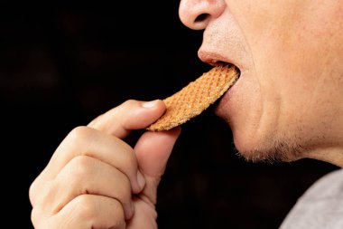 Stroopwafel yiyen tanınmayan bir adamın yakın çekimi. Tatlı Hollanda kurabiyesi. Hollanda waffle 'ı. Güzel karamelli kurabiye..