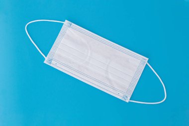 Mavi arka plan üzerine yeni bir yüz maskesi gerilmiş. Geleneksel tıbbi maske.