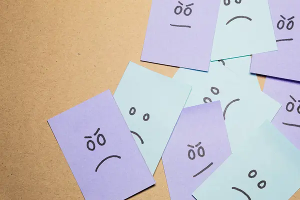 Angry and happy face messed up on an office bulletin board. Sticky notes. Concept of negative human emotions.