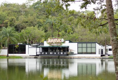 Melgar, Colombia - April 6, 2024. Jurasico, a restaurant and Bar in the ecopark of the Cafam vacation center, Melgar in Tolima, Colombia. Dinosaur themed restaurant in front of a lake. clipart