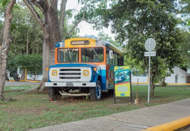 Melgar, Colombia - April 6, 2024. People taking a bus Cafachiva or simply Chiva a colorful rural bus in front of the entrance of Cafalandia, a family park located in the Cafam resort, Melgar in Tolima Colombia. clipart