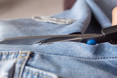 Kotları kesen makasın yakın çekimi. Kot ceketin kolu. Terzilik kavramı.