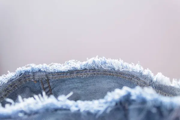 Kot kumaşın yıpranmış kenarına yakın çekim. Yıpranmış kot. Kopyalama alanı olan resim.