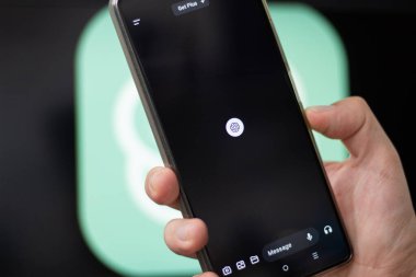 Bogota, Kolombiya - 14 Mayıs 2024: ChatGPT mobil versiyon için koyu temalı ana ekran. Adamın biri cep telefonunda Al tabanlı bir sohbet uygulaması tutuyor. Arka planda ChatGPT logosu bulanıklaştı. Al!.