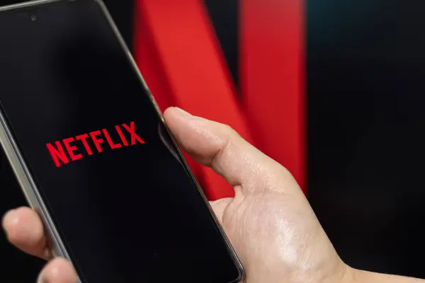Bogota, Colombia - May 14, 2024: Hand holding a cell phone with the Netflix app on the screen. Netflix logo out of focus in the background. Streaming platforms.