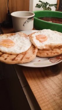 İki arepalı bir tabak ve bir fincan çikolatalı iki sıcak yumurta. Lezzetli tipik Kolombiya kahvaltısı.