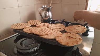 Bir kadın, Kolombiya arepalarıyla dolu bir tencerenin yanında küçük bir tavada yumurta açıyor. Kolombiya 'da tipik bir kahvaltı hazırlıyorum..