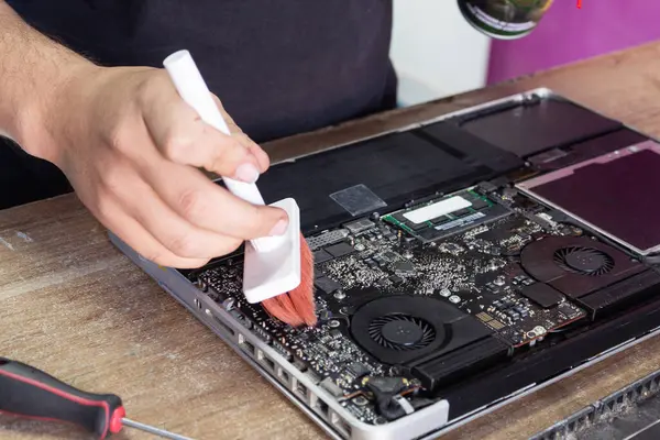 Parçalanmış bir dizüstü bilgisayarı temizleyen bir adam. Bilgisayar tamiri. Teknoloji teknisyeni..