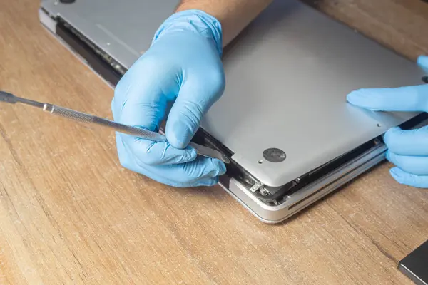 Bilgisayar bakımı. Lateks eldivenli bir adam dizüstü bilgisayarı ortaya çıkarıyor. Çalışma aracı.;