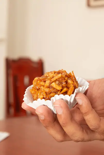 stock image A male hand holds a fresh cocada inside a house, background out of focus. Coconut based dessert.