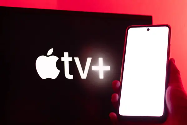 Bogota, Kolombiya - 12 Temmuz 2024: Ön planda boş ekranlı akıllı telefon ve arka planda yatay ekranda Apple TV Plus logosu. Seriler ve film platformu.