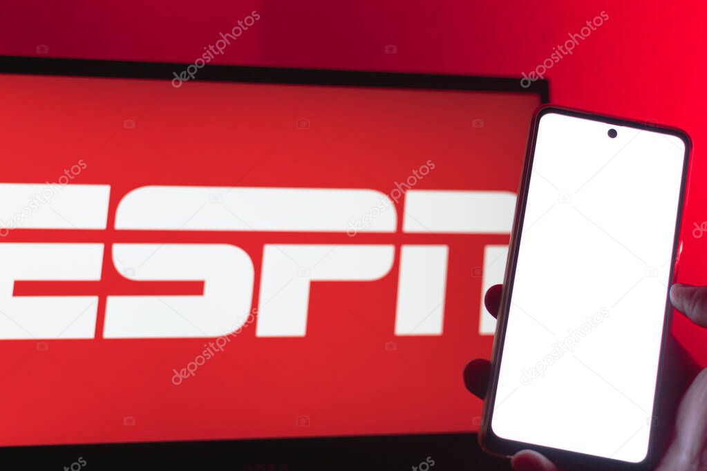 Bogota, Colombia - July 12, 2024: Cell phone with blank screen in front of a TV screen with ESPN logo. App for streaming sporting events. TV channel.